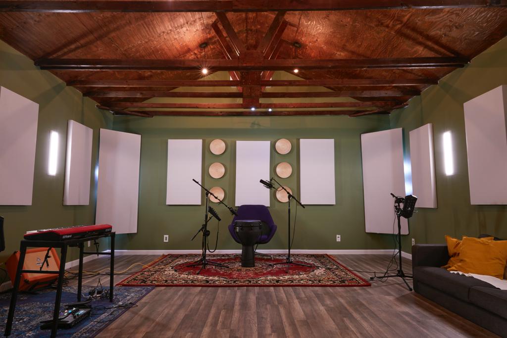 Complete live room with exposed wooden beams, microphones, keyboard, patterned rug and sofa