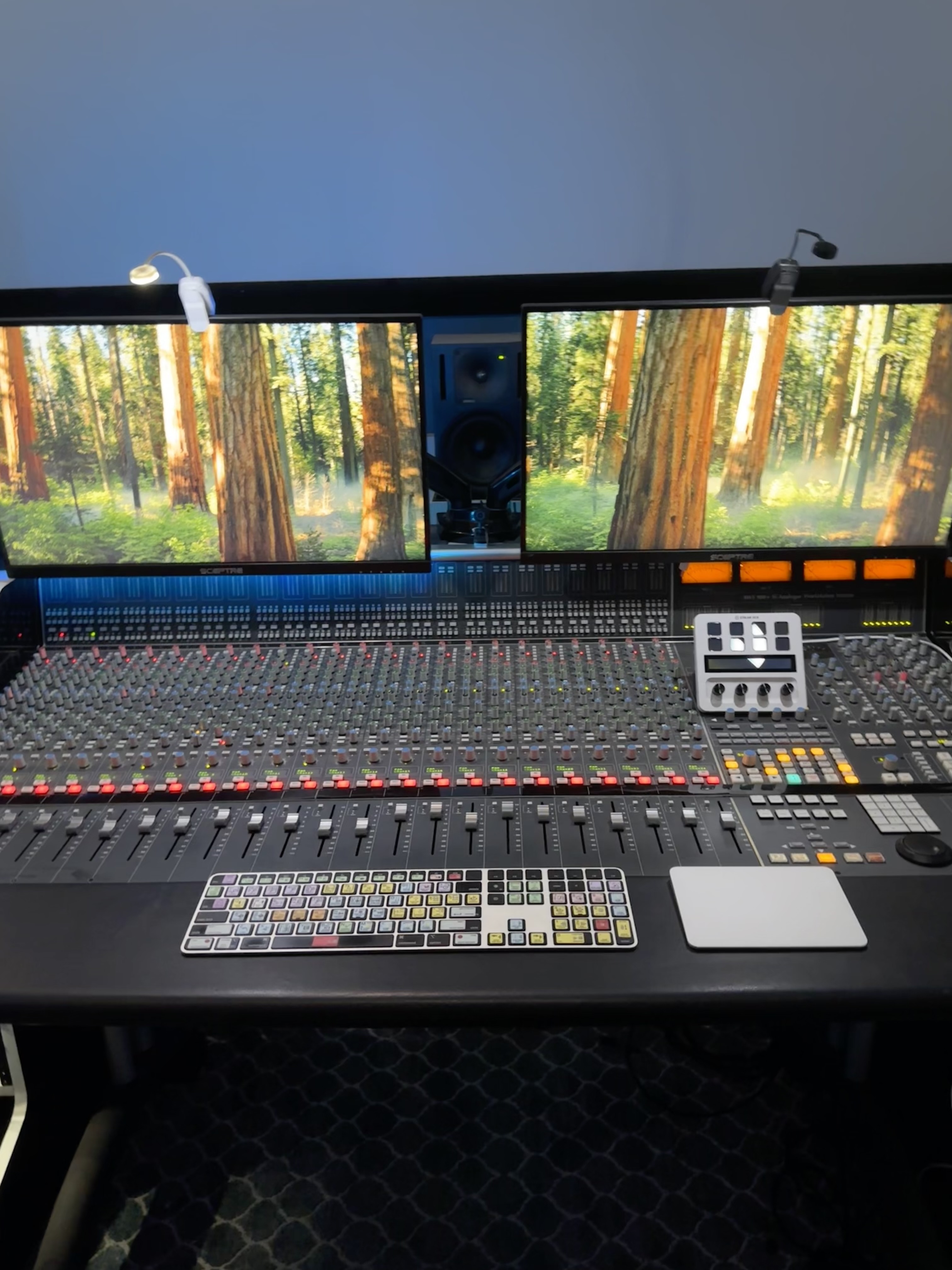 Close view of the SSL console faders, meters and studio screens
